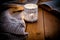 Lit candle in a lace candle holder, knitted sweater and an open book on wood background, cozy atmosphere