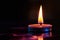 A lit candle sits on a table against a black background, emitting a warm glow in a dimly lit room, Binary flame for a candle on a