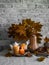 Lit candles, dry maple leaves, pumpkin, stack of books - autumn still life interior decoration house. Cozy home concept