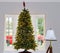 Lit Christmas tree in front of bay window with red truck parked outside showing