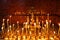 Lit church candles in a gilded candlestick in a temple in the dark. yellow wax lighted candles stand in the church, glow