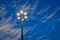 Lit hexagonal streetlight under dramatic sky.