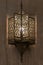 Lit, Moroccan, Arabian lamp with intricate decor hanging on wall.