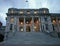 Lit old Edwardian parliament in grey stone with classic colonnade entry atop grand stairs at twilight, Wellington, New Zealand