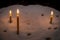 Lit prayer candles standing in sand at a church