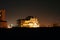 Lit up beach mansion against night skyline