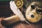 Literature concept. Still life with feather on scroll near venetian mask, old books and vintage clock on wooden table. Vintage ton