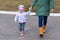 Litle girl holding woman hand and walking outdoor