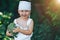 litle happy smiling farmer boy in white overalls and grey hairband holding fresh organic broccoli in hands. garden, harvest season