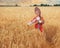 Littl girl kid in Russian national sarafan and a kokoshnik standing in a golden wheat field in summer day