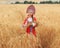 Littl girl kid in Russian national sarafan and a kokoshnik standing in a golden wheat field in summer day