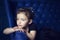 Little 5 years cute beautiful girl lays on blue sofa. Hands under chin. Child in black clothes looks away and thinks. Portrait of