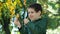 A little 6-year-old boy looks through a magnifying glass at a yellowed birch leaf in autumn in the park