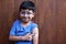 Little 6-year-old Latino boy with glasses and a blue shirt shows his arm with a bandage because he has just been vaccinated agains