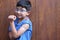 Little 6-year-old Latino boy with glasses and a blue shirt shows his arm with a bandage because he has just been vaccinated agains