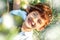 Little 7 years old smiling girl with stylish short haircut laying down in grass under blooming cherry tree in spring. Happiness