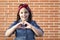 Little activist girl forming heart with her hands isolated on brick wall. Love and feminist future