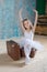 Little adorable ballerina in white tutu with old vintage suitcase in a beautiful studio. Travel and voyage. Concept of growing up