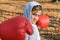 Little adorable girl child in a tracksuit, with a hood on his head, in red boxing gloves, boxing on the street in the autumn fores