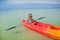 Little adorable girl rowing a boat in blue clear