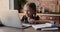 Little adorable girl studying at home using laptop