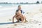 Little adorable and sweet siblings playing together in sand beach with small brother hugging his beautiful blond young sister enjo