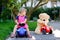Little adorable toddler girl driving toy car and having fun with playing with plush toy bear, outdoors. Gorgeous happy