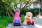 Little adorable toddler girl driving toy car and having fun with playing with plush toy bear, outdoors. Gorgeous happy