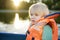 Little afraid boy boating on a river or pond at sunny summer day. Quality family time together on nature. Safety