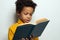 Little African American child boy reading a book on white background. Black kid student portrait