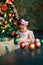 A little African-American girl in a pink dress is playing with Christmas balls to decorate the Christmas tree. a child decorates a