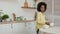 Little African American girl removes deep white bowls from table and places them in sink to wash. End of the meal