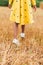 Little african american girl in a trendy yellow polka dot dress and white athletic shoes walks along a yellow beveled field