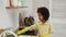 Little African American girl wearing yellow rubber gloves with washcloth wipes surface of electric stove.Teenage girl