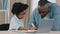 Little african american kid schoolgirl sitting at desk doing homework mature dad helps daughter with lessons home