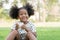 Little African kid girl smiling with dirty smeared lips milk and broken tooth. Cute child holding a glass of milk and sitting on g