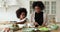 Little afro ethnicity kid girl helping biracial mommy preparing food.