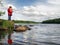 Little angler girl fishing on lake with rod