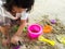 Little Asia girl sitting in the sandbox and playing whit toy shovel bucket