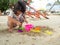 Little Asia girl sitting in the sandbox and playing whit toy shovel bucket and she was scooping in toy shovel bucket.