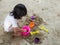 Little Asia girl sitting in the sandbox and playing whit toy shovel bucket and she was scooping in toy shovel bucket.