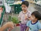 Little Asian babies looking at green fresh broccoli in their mother`s hand