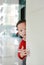 Little Asian baby boy hide behind a corner room. Small children playing peekaboo game indoor