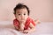 Little Asian baby, cute toddler dressed in red practicing crawling on the bed and looking at the camera