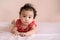 Little Asian baby, cute toddler dressed in red practicing crawling on the bed and looking at the camera