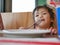 Little Asian baby girl eating tomato ketchup by herself at a restaurant