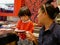 Little Asian baby girl enjoys picking raw ingredients, for her mother, for hotpot cooking, serving on a moving conveyor belt