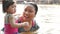 Little Asian baby girl enjoys playing water in a river with her auntie