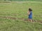 Little Asian baby girl enjoys walking in a field in a rural area
