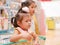 Little Asian baby girl having fun standing in a shopping cart with her sister seeing many products for sale